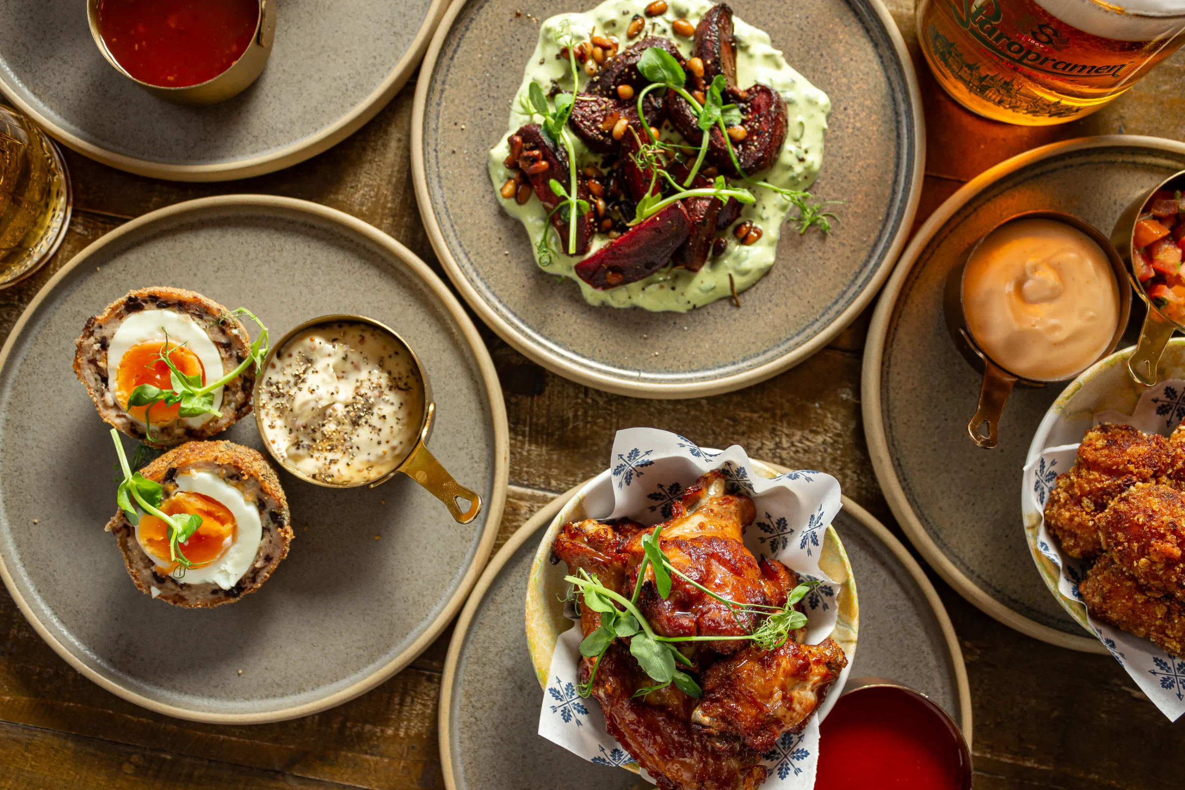 Flat lay of assorted pub food small plates and beers