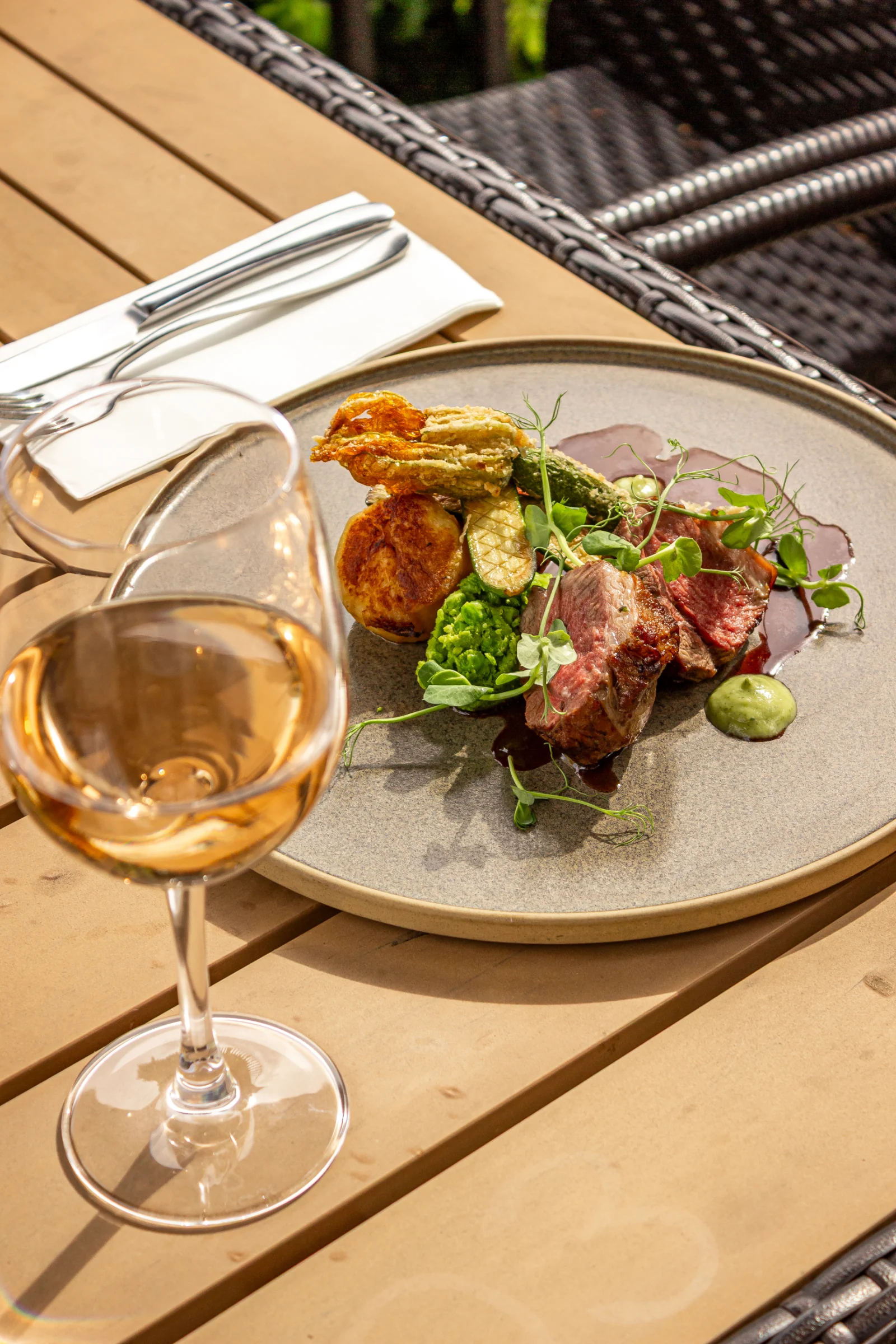 Lamb dish paired with a glass of wine on the outside terrace at The Cross Scythes Totley